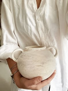 a woman holding a white vase in her hands