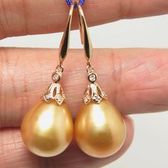 "Lovely in house designed dangle earrings, made of 14k solid yellow gold with 14 natural mine small accent diamonds & a natural GOLDEN, south sea cultured pearls from Australia. Each of the large 'Find Drop' pearl exhibits excellent high luster and thicker nacre. The pearls also possesses a silky smooth surface with just a minimal natural spots/blemish. Style: Hook. Metal Purity: 14k Solid Yellow Gold. Genuine Diamond: 14 pcs / 0.059 ctw. Earring approx. Length (including pearl): 1.4 inches Luxury Gold Pear-shaped Diamond Earrings, Yellow Gold Diamond Pear-shaped Earrings, Exquisite Gold Pearl Earrings With Diamond Accents, Exquisite Gold Drop Earrings, Gold Diamond Dangle Pearl Earrings, Gold Pear-shaped Diamond Earrings With Accents, Gold Drop Pearl Earrings With Diamond Accents, Exquisite Gold Dangle Diamond Earrings, Pear-shaped Yellow Gold Earrings With Diamond Accents