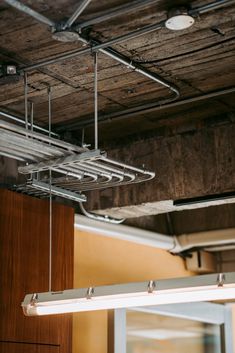 the lights are hanging from the ceiling in an office building with exposed wood and metal beams