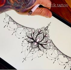 a person's hand holding a marker and drawing on paper with an intricate design