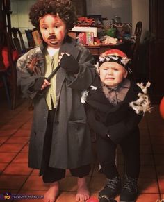 two children dressed up in costumes standing next to each other on tiled floored room floor