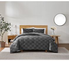 a bed with grey and white checkered comforter in a room next to a table