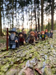 a group of lego minifigures sitting on top of a moss covered tree trunk