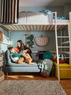 a woman sitting on top of a blue couch under a bunk bed