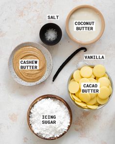 four bowls with different ingredients labeled in them on a white surface, including coconut butter, cacoa sugar and salt