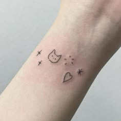 a small wrist tattoo with cats and stars in the sky on it's left arm