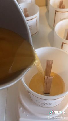 a person pours liquid into a cup with wooden spoons in front of them