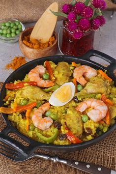 a skillet filled with rice, shrimp and peas