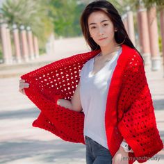 a woman is wearing a red crocheted shawl