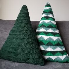 two knitted christmas trees sitting on top of a gray couch next to each other