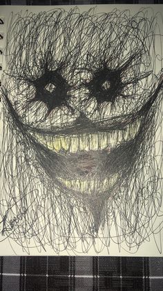 a drawing of a smiling face made out of black and white yarn on a sheet of paper