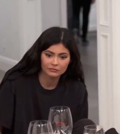 a woman sitting at a table with wine glasses