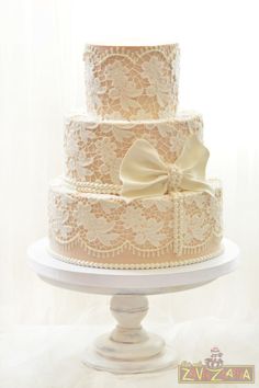 a three tiered wedding cake with a bow on top