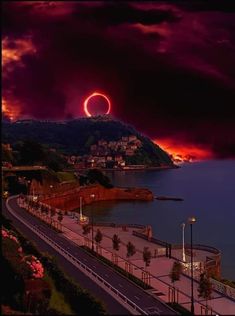 an eclipse is seen in the sky over a body of water at night with pink clouds