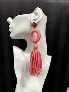 a white mannequin with pink tassels and a gold earring on it