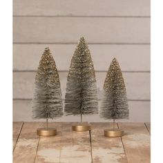 three small christmas trees sitting on top of a wooden table