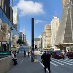 people are walking on the sidewalk in front of tall buildings