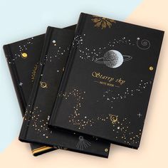 three black notebooks with gold foil stars and the words saturn sky written on them