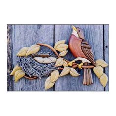 a wooden bird sitting on top of a tree branch next to a nest filled with leaves