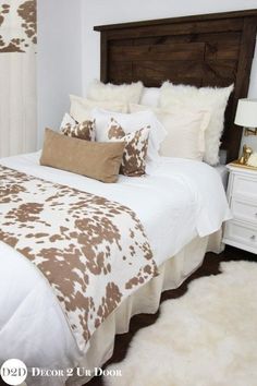 a bed with white and brown pillows on top of it next to a night stand