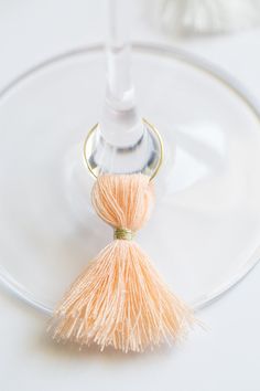 an orange tassel on a wine glass with a white bottle in the back ground