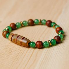 a wooden beaded bracelet with green and brown beads on a wood surface, resting on a table