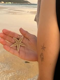 a person holding a starfish in their hand on the beach