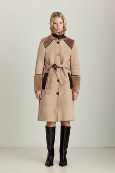 The Astrid is our modernized take on a classic trench coat suited for colder weather. Made from ultra-soft suede shearling with leather trim, statement cuffs, a distinctive buckled collar, and welt pockets, it brings a new level of sophistication to seasonal warmth, no matter what you're wearing or where you're going. Designer Leather Outerwear With Belted Cuffs, Designer Shearling Outerwear For Work, Designer Sheepskin Outerwear For Work, Brown Leather Fur Coat For Workwear, Chic Leather Fur Coat For Work, Classic Sheepskin Fur Coat For Work, Leather Fur Coat With Faux Fur Trim For Work, Designer Winter Outerwear With Belted Cuffs, Classic Trench Coat