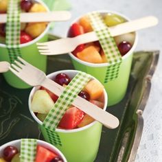 a cookbook with green cups filled with fruit and plastic spoons in each cup