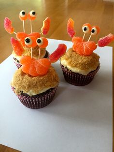 two cupcakes decorated with orange and red candies are sitting on top of a piece of paper