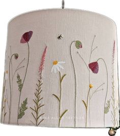 a lampshade with flowers painted on it and a bee sitting on the flower