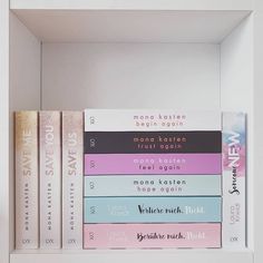 the books are stacked on top of each other in a white shelf with pink and blue covers