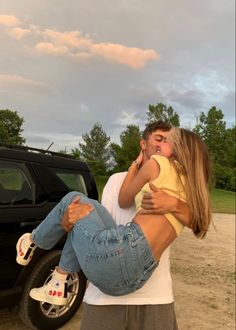 a man holding a woman in front of a truck