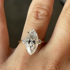 a woman's hand with a diamond ring on top of her finger and an engagement band