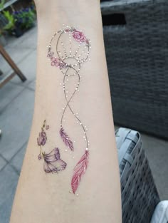 a woman's arm with a tattoo on it that has flowers and feathers drawn on it