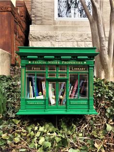 there is a green box with books in it on the ground next to some bushes