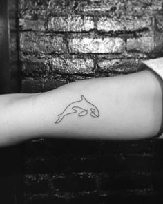 a black and white photo of a person's arm with a dolphin tattoo on it