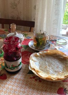 a table topped with plates and bowls filled with food next to a jar of jelly