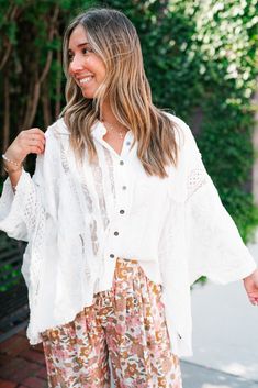 The Lakelyn Lace Ivory Button Up Top is a beautifully crafted, off-white lace and gauze blouse that exudes a romantic, bohemian vibe. The top features a delicate mix of lace and textured fabric, creating a soft and airy look perfect for layering. It has a button-down front with small, dark buttons that add a subtle contrast to the light fabric. The collar is slightly frayed, contributing to its relaxed and effortless style. The sleeves are voluminous and made entirely of intricate lace, adding a Bohemian Blouse With Lace Patchwork For Vacation, Bohemian Beach Blouse With Lace Patchwork, Bohemian Lace Patchwork Blouse For Beach, Bohemian Long Sleeve Crochet Lace Blouse, Bohemian Button-up Blouse For Vacation, Bohemian Long Sleeve Crochet Top For Day Out, Bohemian Crochet Top With Long Sleeves For Day Out, Bohemian Blouse With Lace Sleeves, White Bohemian Crochet Top For Day Out