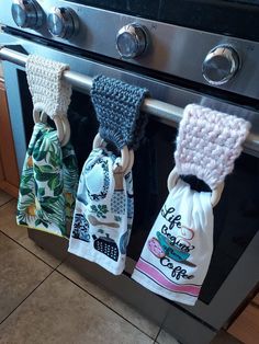 three kitchen towels hanging from the handle of an oven