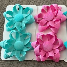 three different colored hair bows are on a white board with blue and pink flowers in the middle