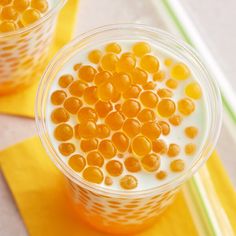 two cups filled with orange jelly on top of a yellow place mat next to each other