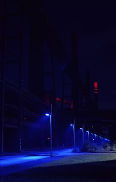 an empty parking lot at night with street lights lit up in the dark and no one around it