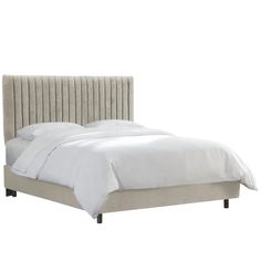 an upholstered bed with white sheets and pillows