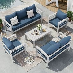 an outdoor patio furniture set with blue cushions and white coffee table next to a swimming pool