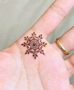 a woman's hand with a ring on it and a tattoo design on the middle finger