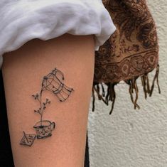 a woman's leg with a tattoo on it that has tea cups and flowers in them