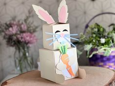 a cardboard bunny sitting on top of a tree stump next to flowers and potted plants