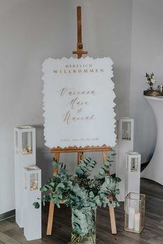 an easel with greenery sits in front of a sign that says welcome to guests