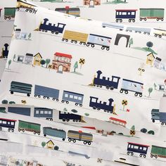 a close up of a pillow case with trains and houses on it's side